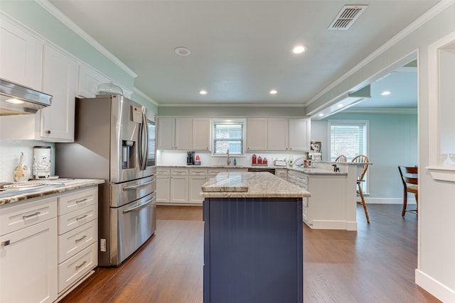 kitchen with visible vents, dark wood-style flooring, a peninsula, and a wealth of natural light