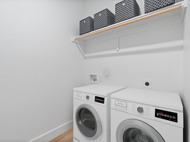 laundry area with laundry area, baseboards, separate washer and dryer, and light wood-type flooring