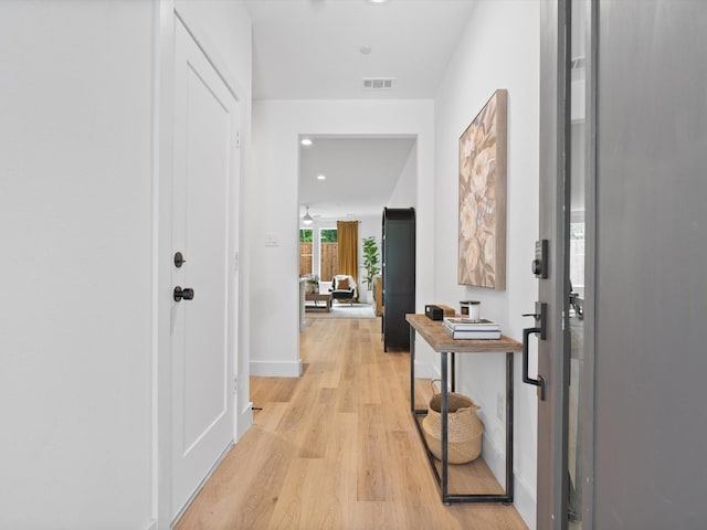 hallway with light wood-type flooring, recessed lighting, baseboards, and visible vents