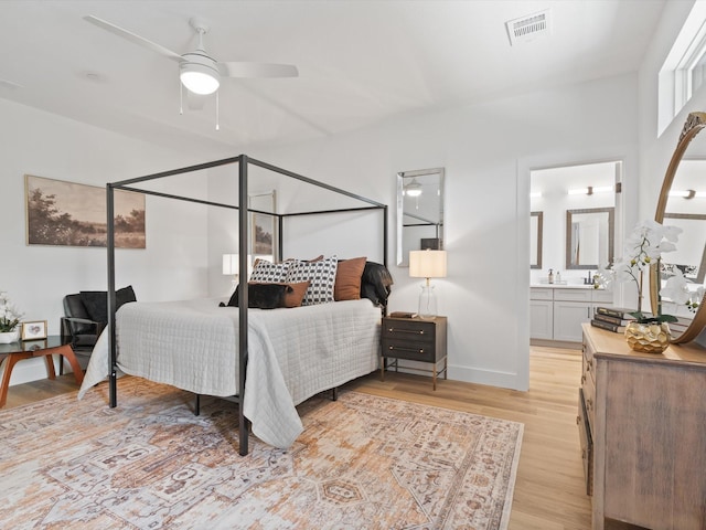 bedroom with light wood-style floors, baseboards, ensuite bathroom, and visible vents
