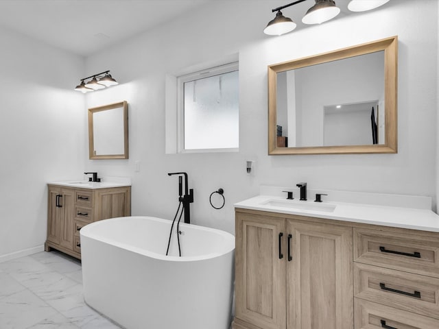 bathroom with a sink, marble finish floor, two vanities, and a freestanding tub