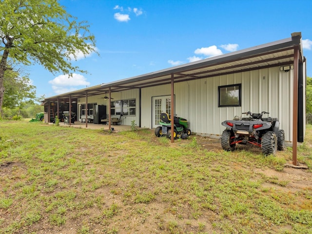 rear view of property featuring board and batten siding, a yard, and a patio area