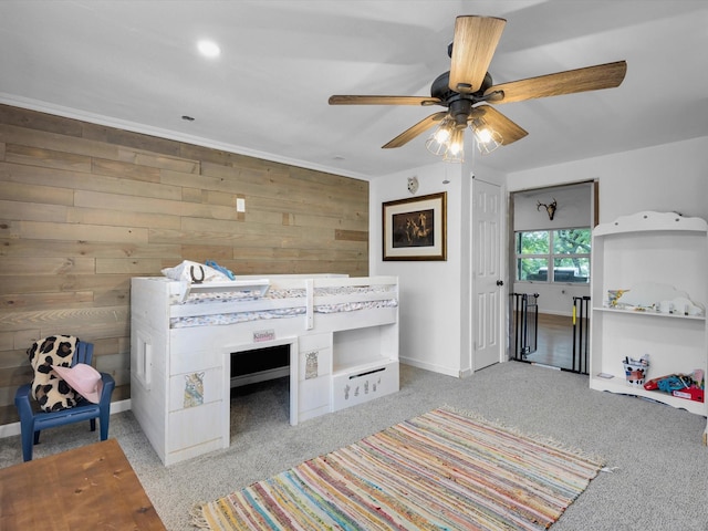 unfurnished bedroom with baseboards, wood walls, carpet, and a ceiling fan