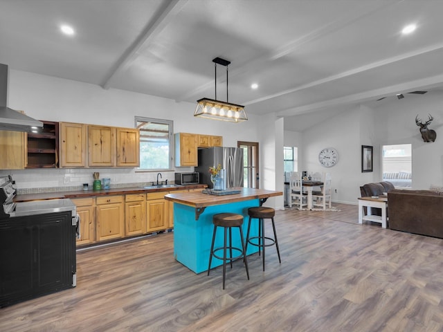 kitchen featuring a kitchen breakfast bar, appliances with stainless steel finishes, tasteful backsplash, a sink, and open floor plan