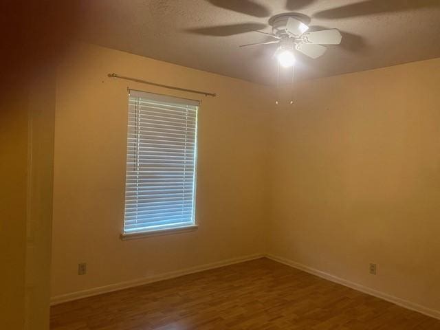 empty room featuring baseboards, ceiling fan, and wood finished floors