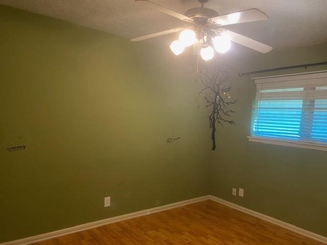 spare room with baseboards, ceiling fan, and wood finished floors