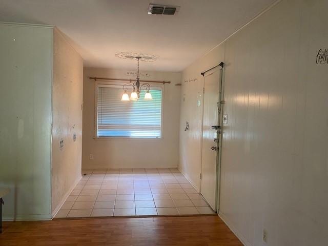 unfurnished dining area featuring baseboards, a chandelier, visible vents, and light wood-style floors