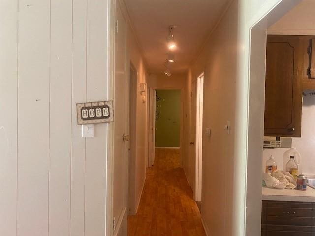 corridor featuring light wood-type flooring and baseboards