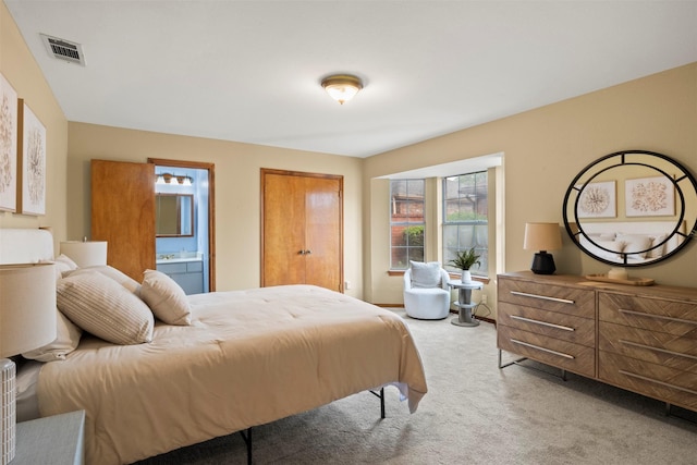 carpeted bedroom featuring visible vents and ensuite bath