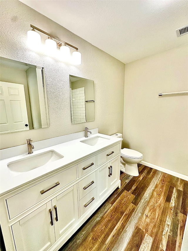 full bathroom featuring a sink, toilet, wood finished floors, and visible vents
