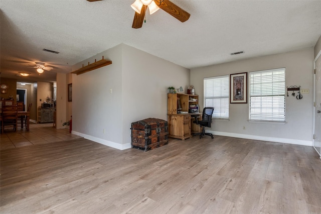 living room featuring a ceiling fan, a desk, wood finished floors, a textured ceiling, and baseboards