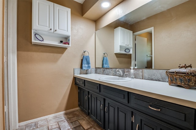 bathroom featuring baseboards, stone finish floor, and vanity