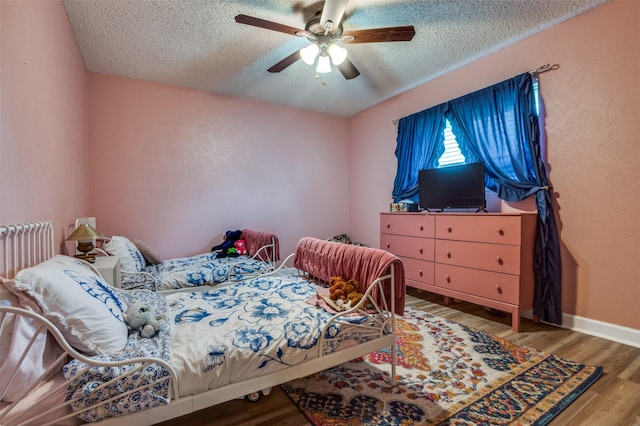 bedroom featuring a textured ceiling, wood finished floors, a ceiling fan, and radiator heating unit