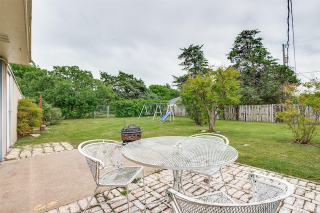 view of patio featuring a playground, an outdoor fire pit, and outdoor dining space