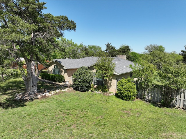 view of property exterior with a lawn, brick siding, fence, and a chimney