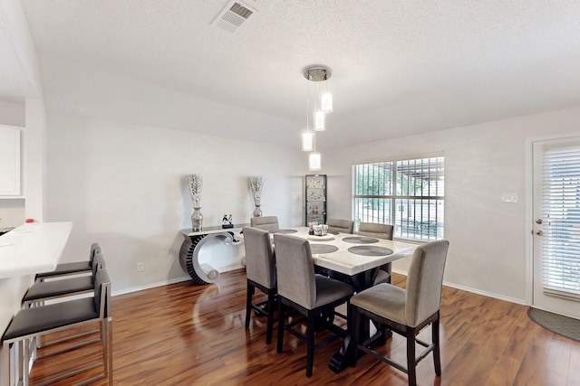 dining space featuring baseboards, wood finished floors, and visible vents