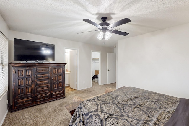 bedroom with ceiling fan, light colored carpet, a walk in closet, baseboards, and ensuite bathroom