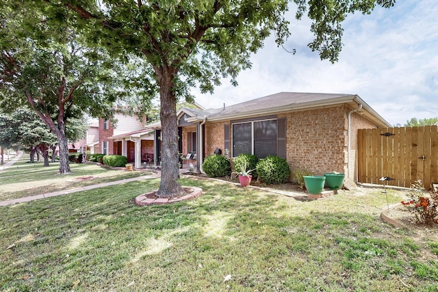 ranch-style home featuring fence, a front lawn, and brick siding