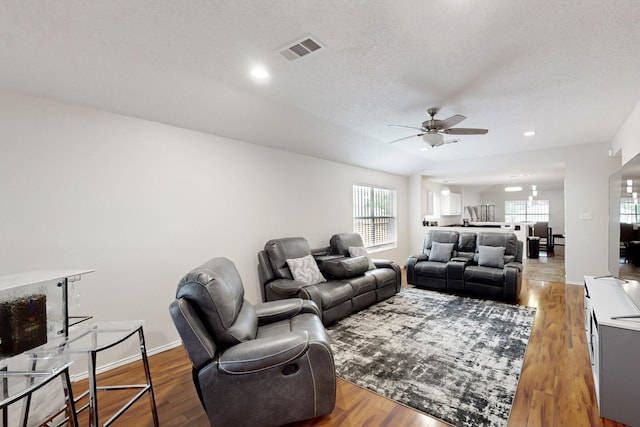 living room with visible vents, a ceiling fan, wood finished floors, and a wealth of natural light