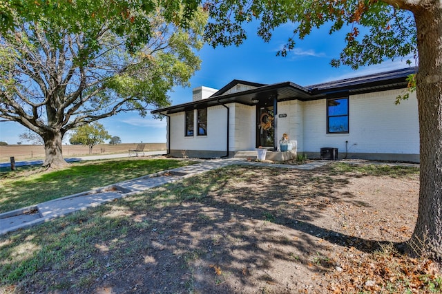 1076 N Cedar St, Muenster, TX 76252 - view of front of house with central air condition unit, a chimney, a front lawn, and brick siding
