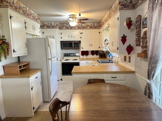 kitchen featuring a ceiling fan, a peninsula, white appliances, light countertops, and a sink