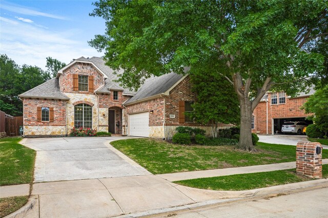 view of front of home featuring a front yard, stone siding, roof with shingles, an attached garage, and driveway