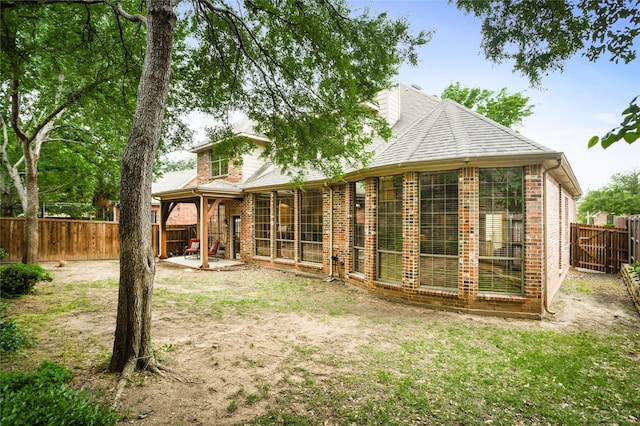 rear view of property featuring a fenced backyard, a patio, and brick siding
