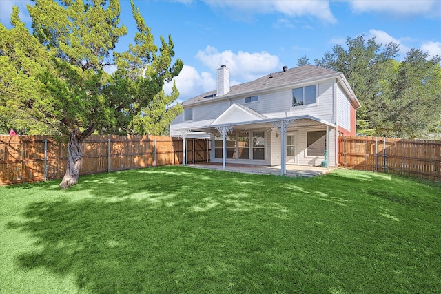 rear view of house featuring a lawn, a chimney, a fenced backyard, and a patio area