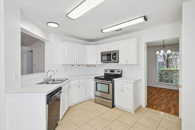 kitchen with appliances with stainless steel finishes, a sink, light tile patterned floors, light countertops, and a notable chandelier