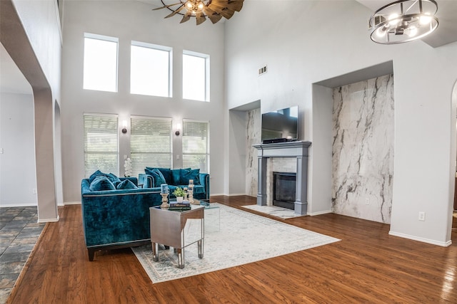 10228 Crawford Farms Dr, Fort Worth, TX 76244 - living area featuring arched walkways, wood finished floors, a tile fireplace, a towering ceiling, and a chandelier