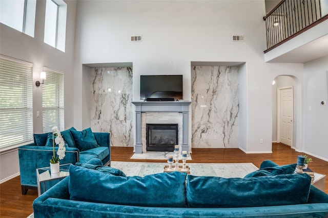 10228 Crawford Farms Dr, Fort Worth, TX 76244 - living room with a high ceiling, a fireplace with flush hearth, arched walkways, wood finished floors, and baseboards