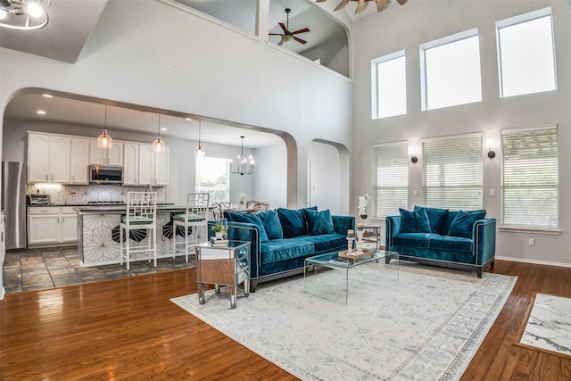 10228 Crawford Farms Dr, Fort Worth, TX 76244 - living room featuring arched walkways, ceiling fan, dark wood-style floors, a high ceiling, and a chandelier
