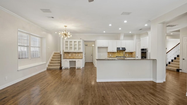 708 Renaissance Ct, Keller, TX 76248 - kitchen featuring under cabinet range hood, oven, ornamental molding, and white cabinetry