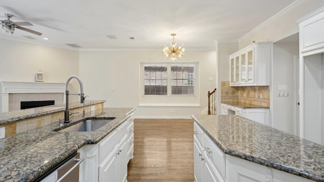 708 Renaissance Ct, Keller, TX 76248 - kitchen with wood finished floors, ceiling fan with notable chandelier, dark stone countertops, a sink, and white cabinets