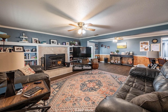 3756 County Road 192, Anson, TX 79501 - living area with crown molding, ceiling fan, a wood stove, a wainscoted wall, and wood finished floors