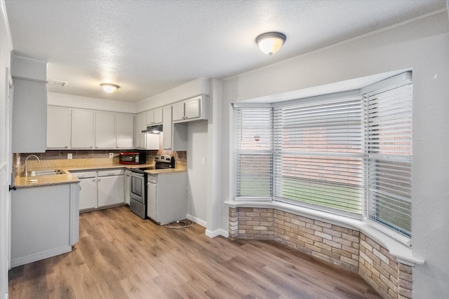 806 Marigold Dr, Cedar Hill, TX 75104 - kitchen with electric range, a textured ceiling, a sink, light wood finished floors, and under cabinet range hood