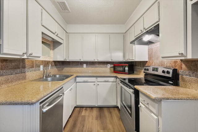 806 Marigold Dr, Cedar Hill, TX 75104 - kitchen with white cabinets, appliances with stainless steel finishes, a sink, wood finished floors, and under cabinet range hood