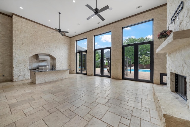 unfurnished living room with crown molding, ceiling fan, and a fireplace