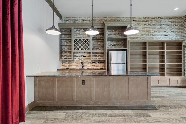 bar with light wood-style floors, freestanding refrigerator, pendant lighting, and brick wall