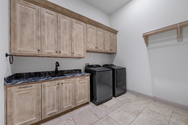 clothes washing area with washing machine and dryer, cabinet space, a sink, baseboards, and light tile patterned floors