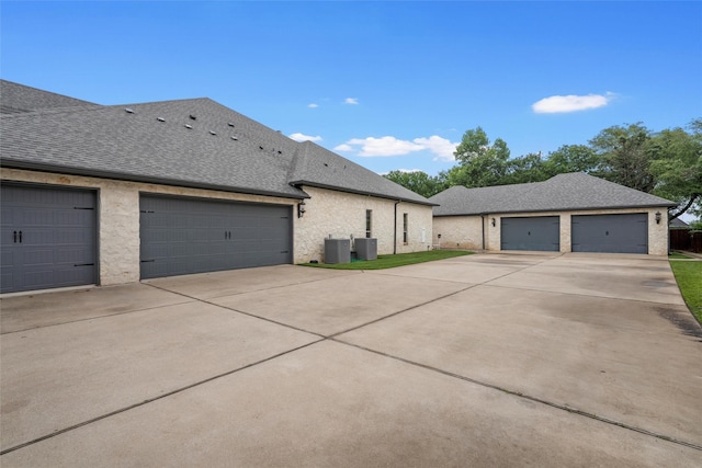 view of front of property featuring central AC, driveway, a shingled roof, and a garage