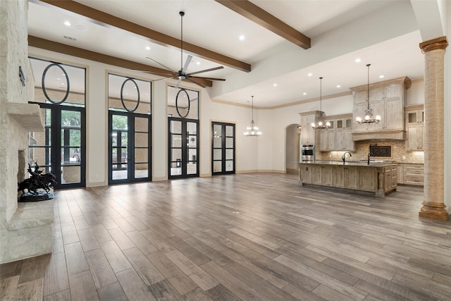 unfurnished living room featuring a sink, beam ceiling, ceiling fan with notable chandelier, recessed lighting, and dark wood-style floors