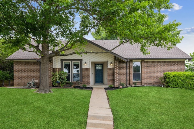 ranch-style house featuring brick siding, a front yard, and roof with shingles