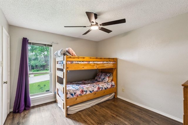 bedroom with a textured ceiling, ceiling fan, baseboards, and wood finished floors