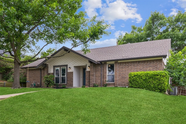ranch-style house with brick siding, cooling unit, a front yard, and roof with shingles