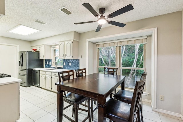 dining space featuring visible vents, a textured ceiling, ceiling fan, and light tile patterned floors