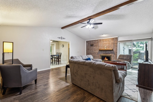 living area with ceiling fan, a fireplace, a textured ceiling, vaulted ceiling with beams, and dark wood-style floors