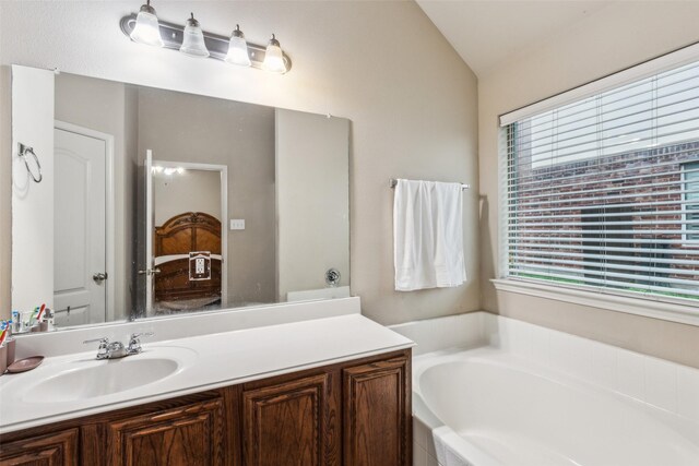 full bath with a garden tub, vaulted ceiling, and vanity