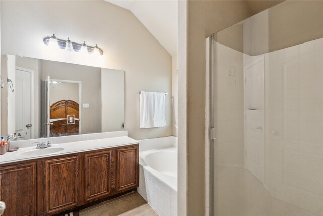 ensuite bathroom with a garden tub, a stall shower, tile patterned flooring, vanity, and vaulted ceiling