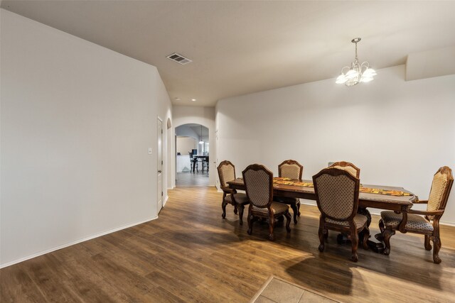 dining space with arched walkways, wood finished floors, a chandelier, baseboards, and recessed lighting